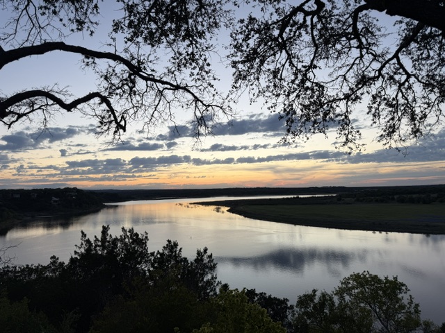 Central Texas sunset over the river, framed by live oak branches
